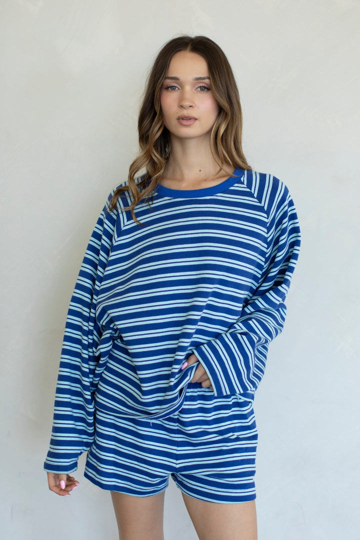 Woman wearing a blue and white striped outfit against a plain background