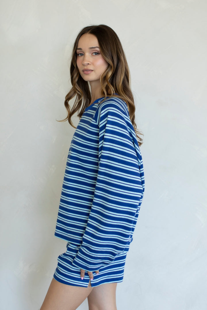 Woman wearing a blue and white striped shirt and shorts against a plain background