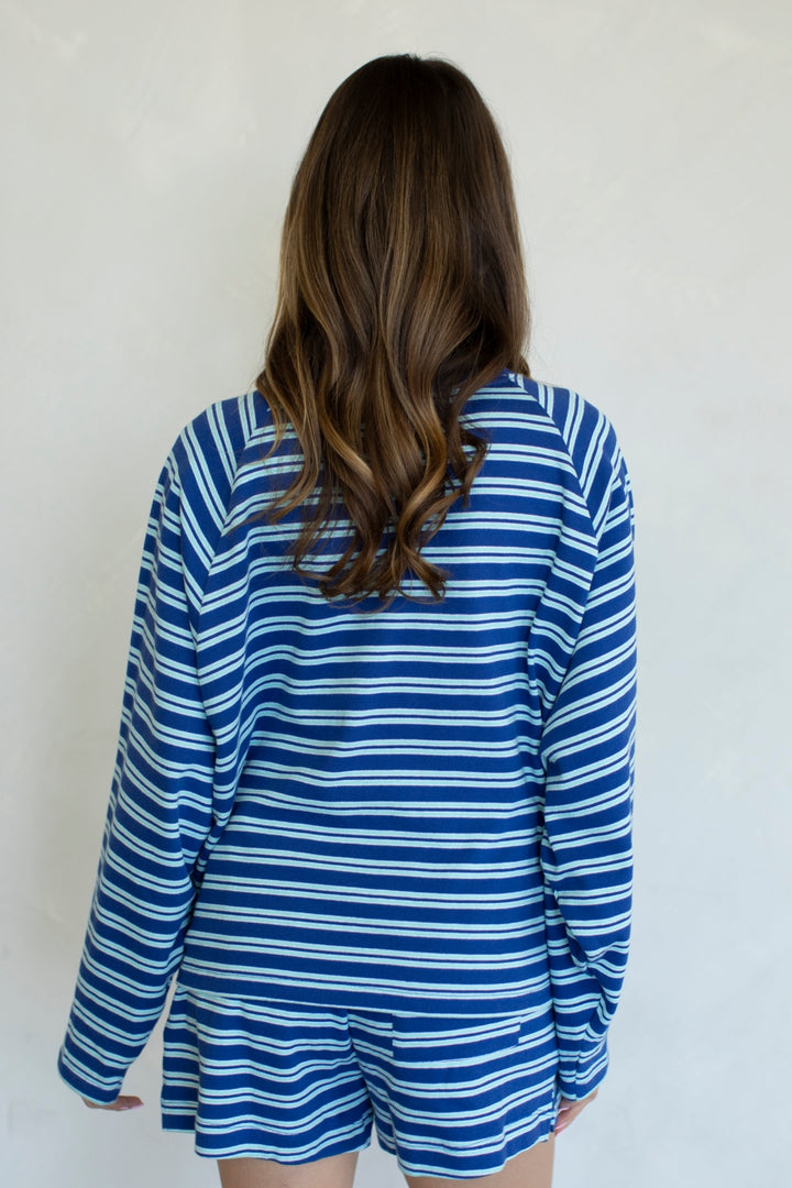 Person wearing a blue and white striped shirt and shorts against a plain background