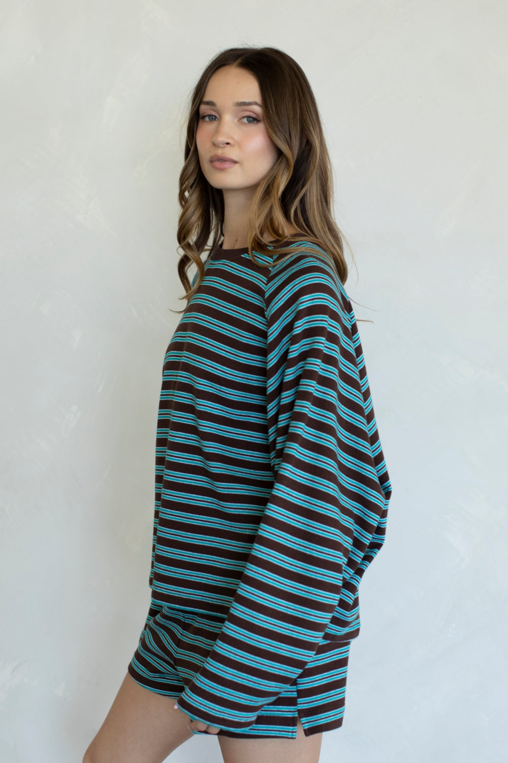 Woman wearing a blue and brown striped dress against a white background