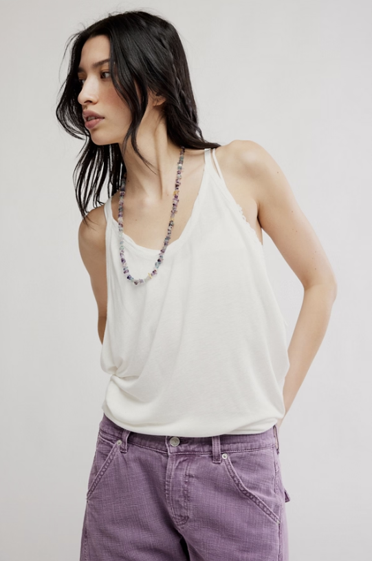 Woman wearing white tank and purple pants on white background