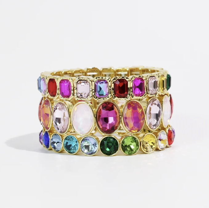 Stack of rainbow gemstone and gold bracelets on white background