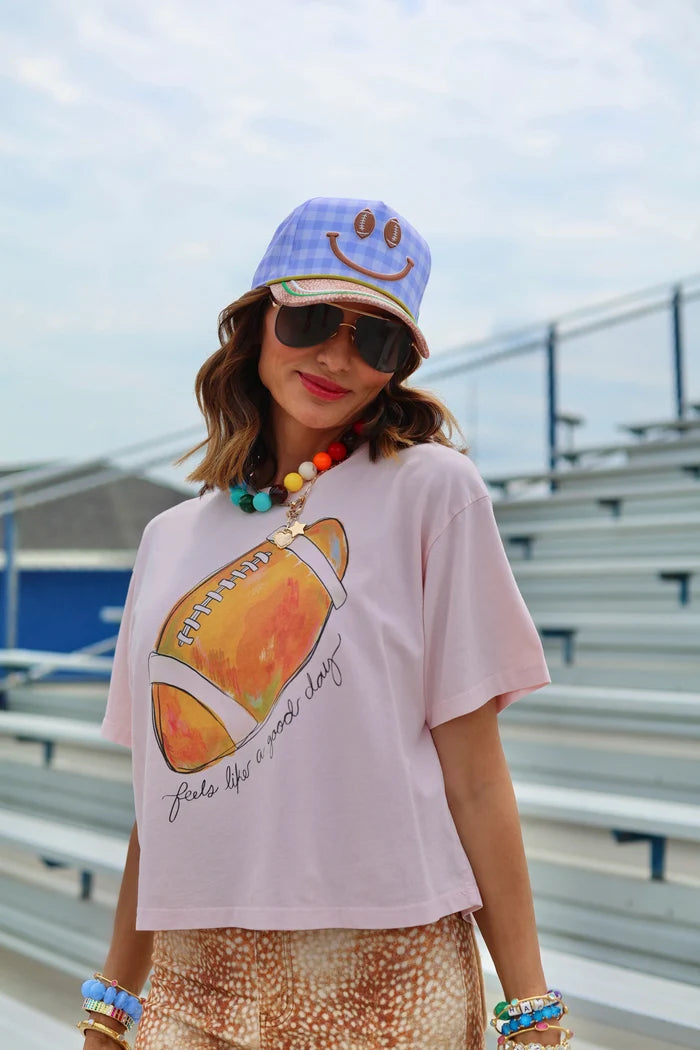 Woman wearing trucker hat and football theme tee standing in bleachers