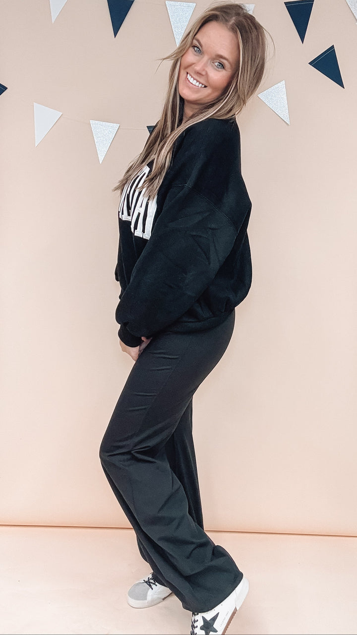 woman wearing black sweatshirt and pants on plain background