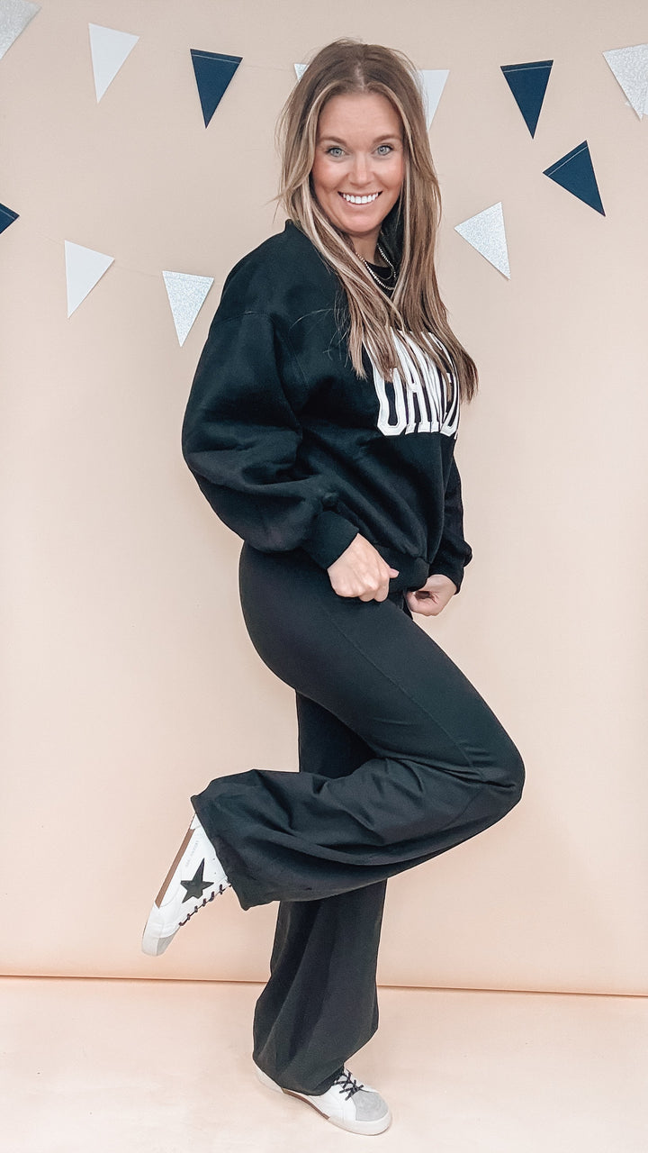 Woman wearing black sweatshirt and pants on plain background