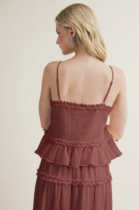 A woman shown from the back wearing a dusty rose tiered spaghetti-strap dress against a plain beige studio background.
