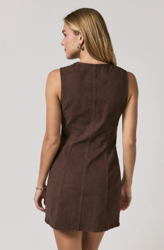 A woman shown from the back wearing a sleeveless brown dress against a plain light gray studio background.