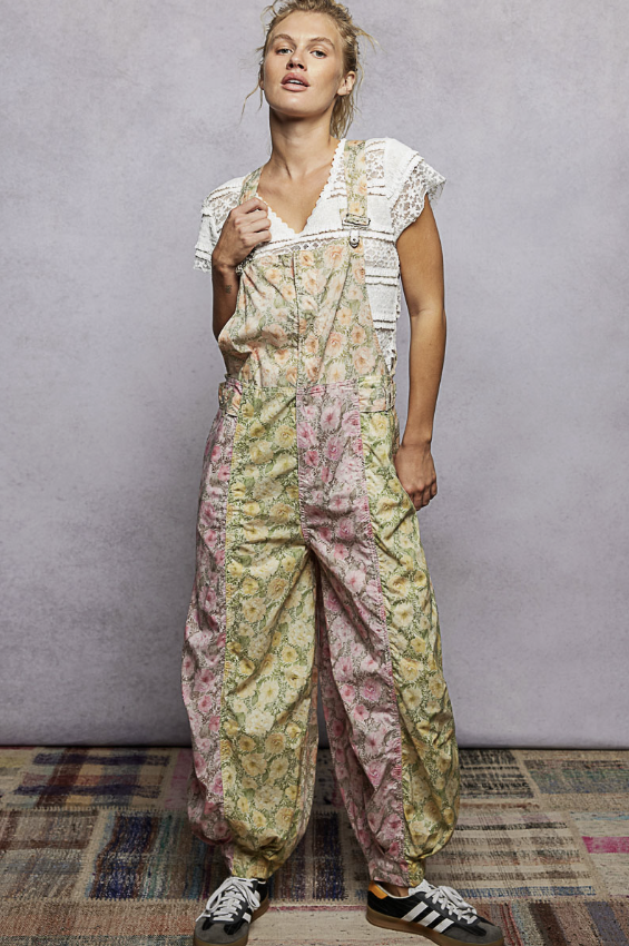 Woman wearing pink and yellow floral overalls on plain background