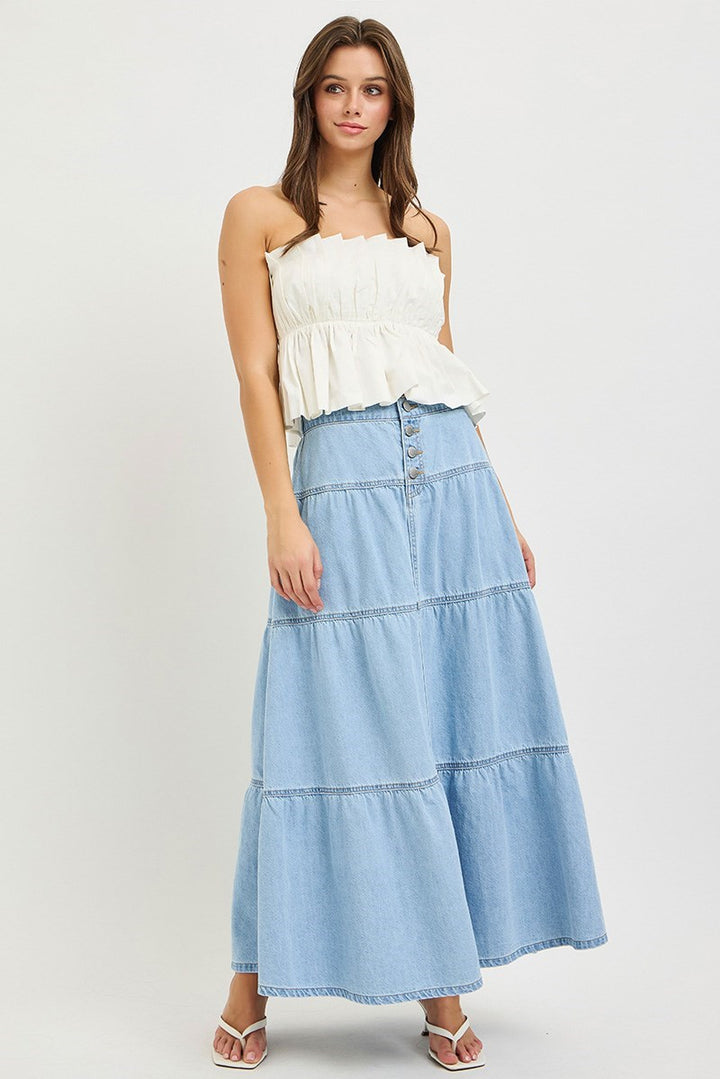 Woman wearing denim maxi skirt and white top on plain background