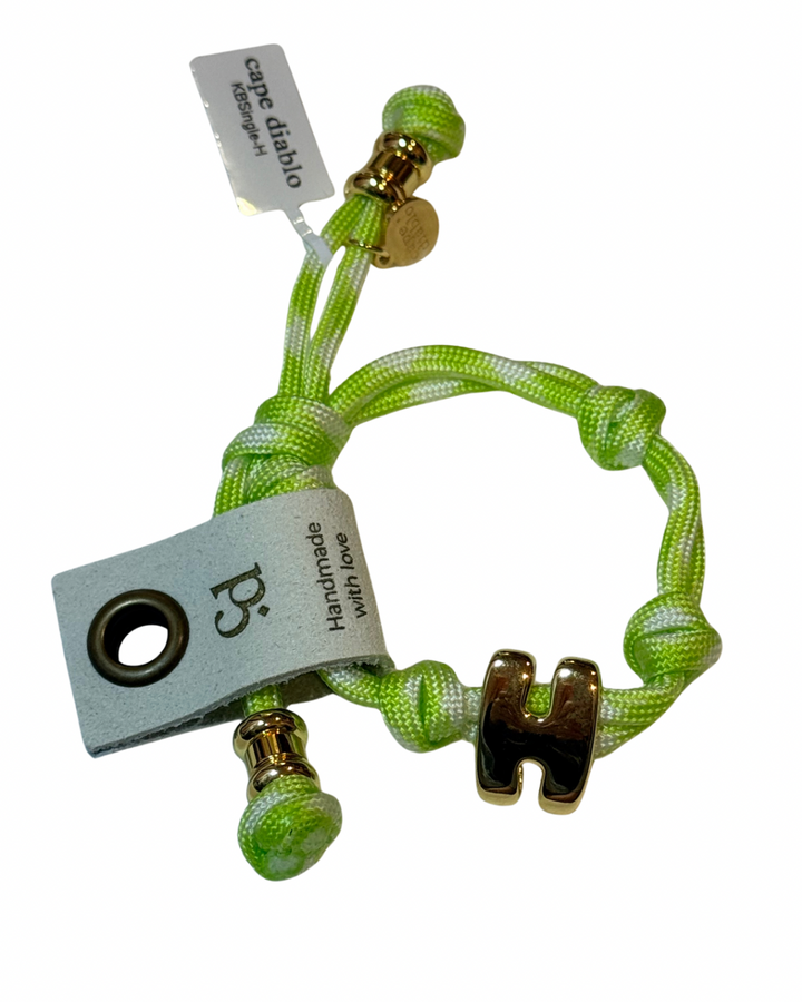 Green braided bracelet with gold accents and a visible brand tag on a white background