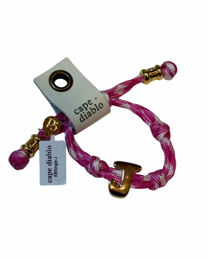 Cord bracelet with gold accents on plain background