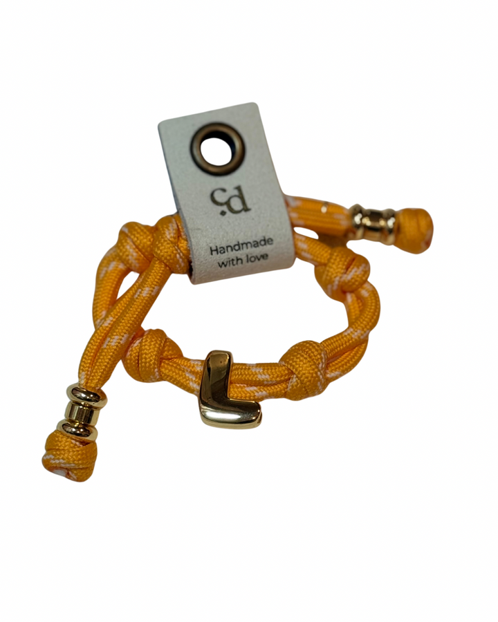 Cord bracelet with gold accents on plain background