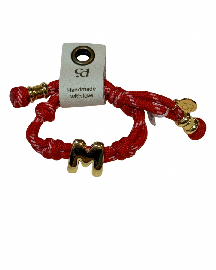 Red bracelet with gold letter 'M' charm and 'Handmade with Love' tag on a white background