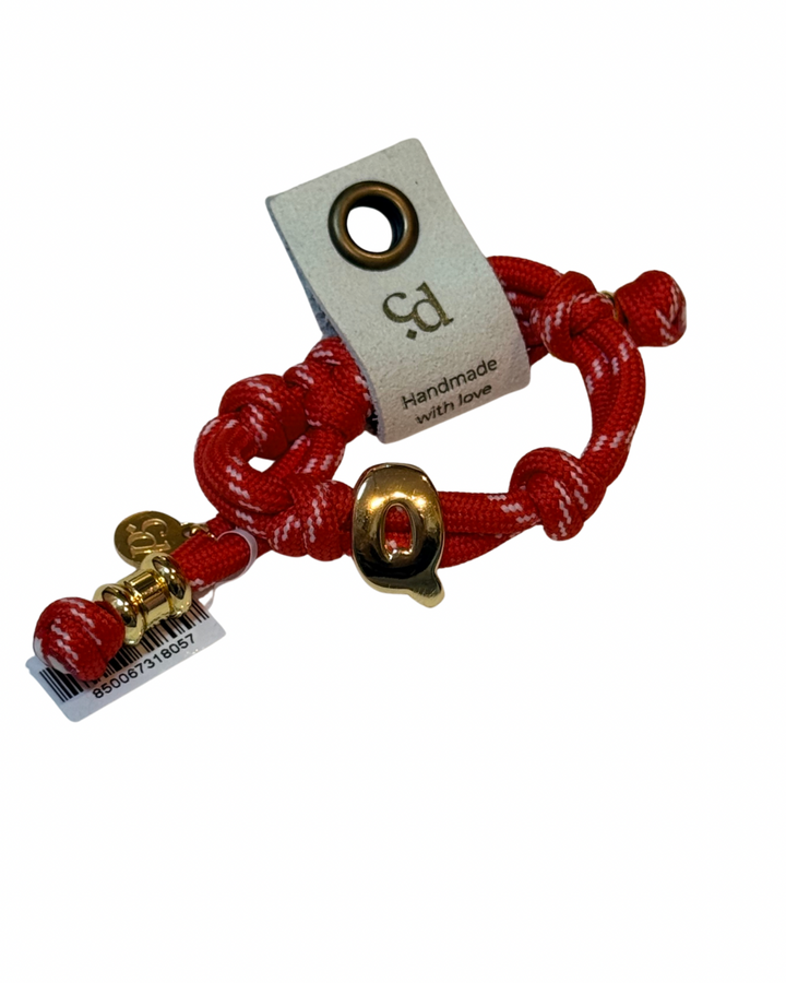 Red braided bracelet with gold accents and a tag on a white background