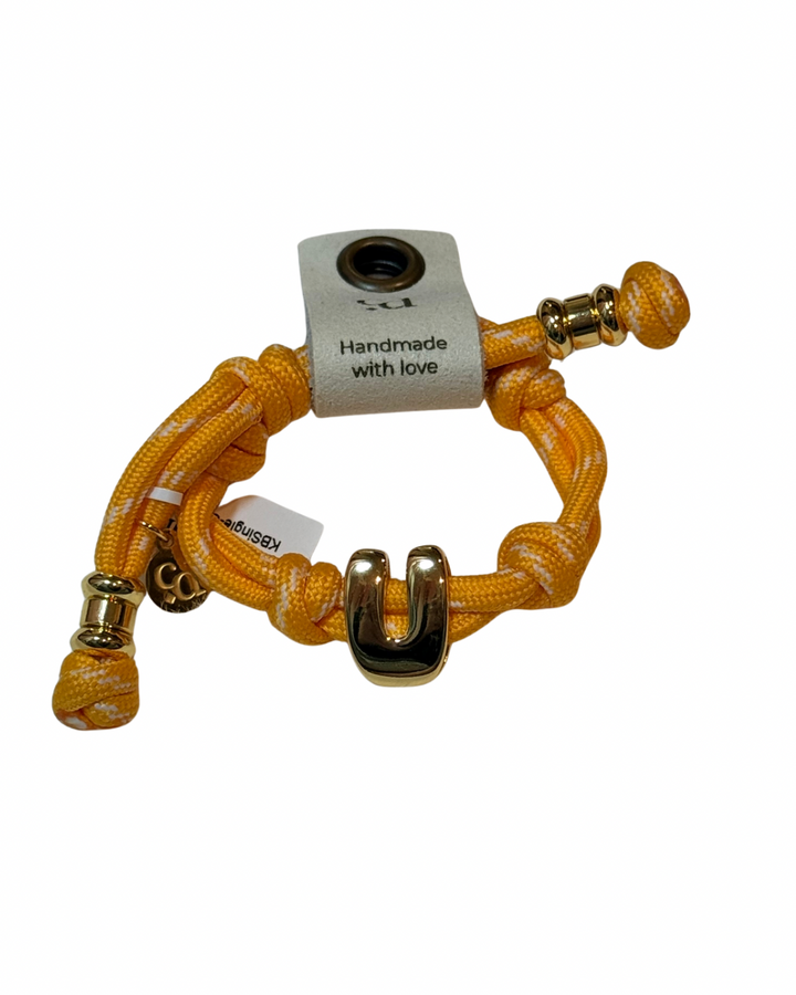 Yellow braided bracelet with gold accents on a white background