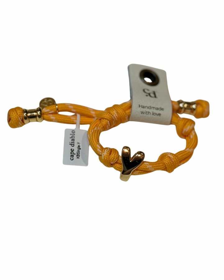 Cord bracelet with gold accents on plain background