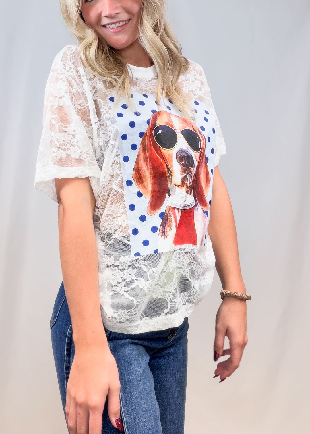 Woman wearing white lace short sleeve shirt with beagle graphic and denim jeans on plain background