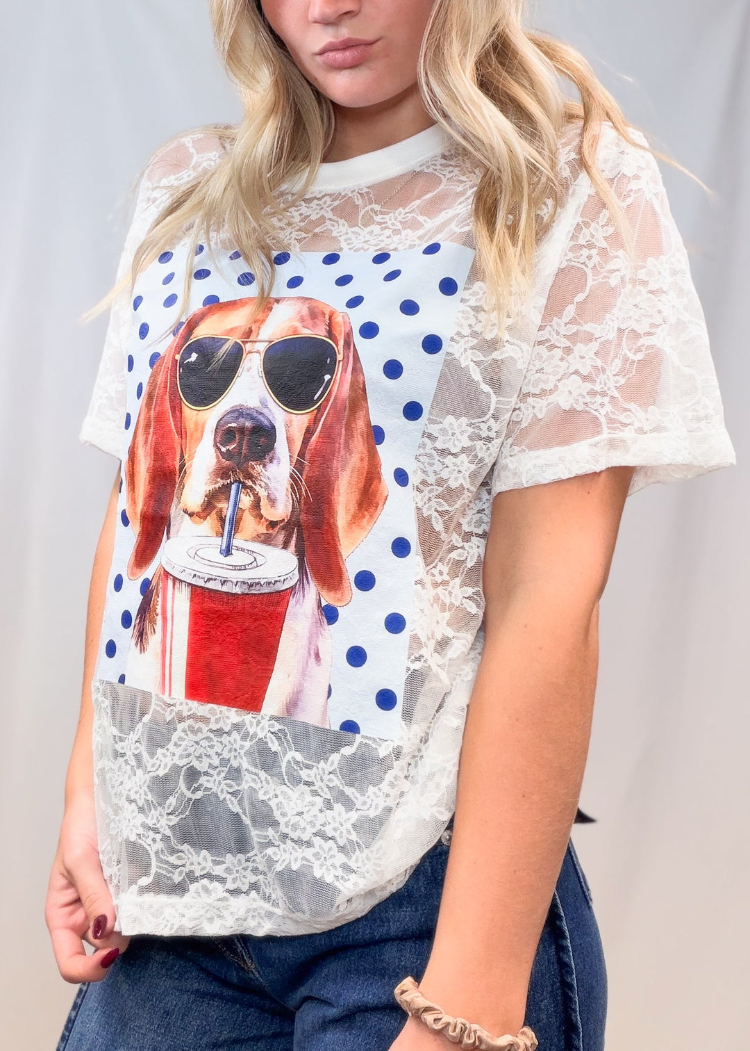 Woman wearing white lace tee with beagle graphic and denim jeans on plain background