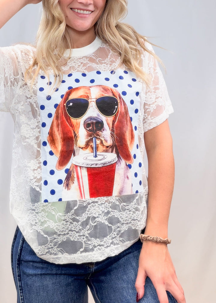 Woman wearing white lace tee with beagle graphic on front with denim jeans on plain background