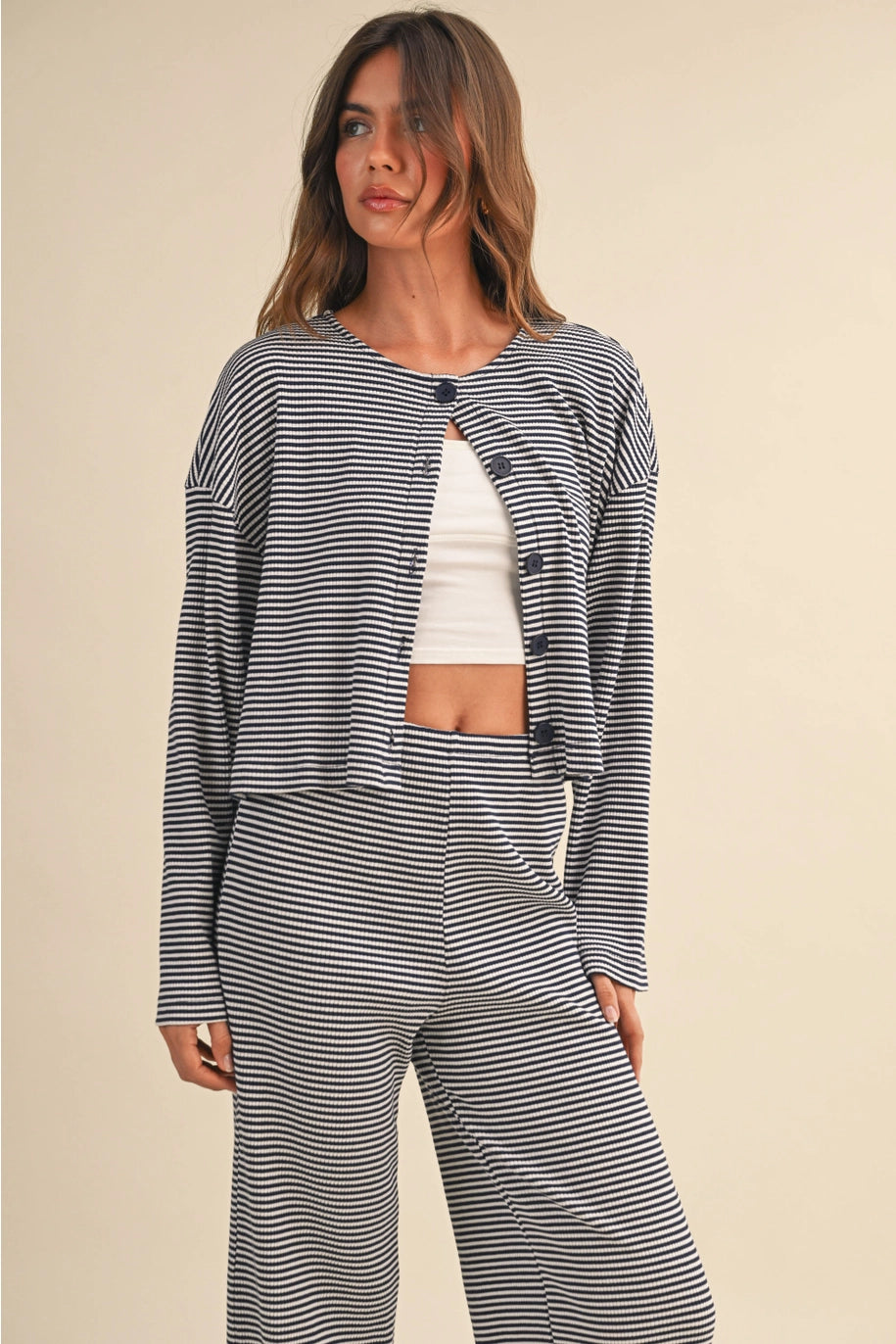 Woman wearing a navy and white striped outfit on a beige background
