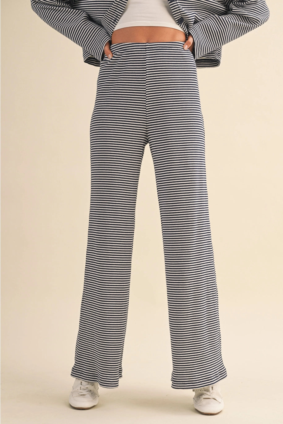 Person wearing navy and white striped pants on a beige background