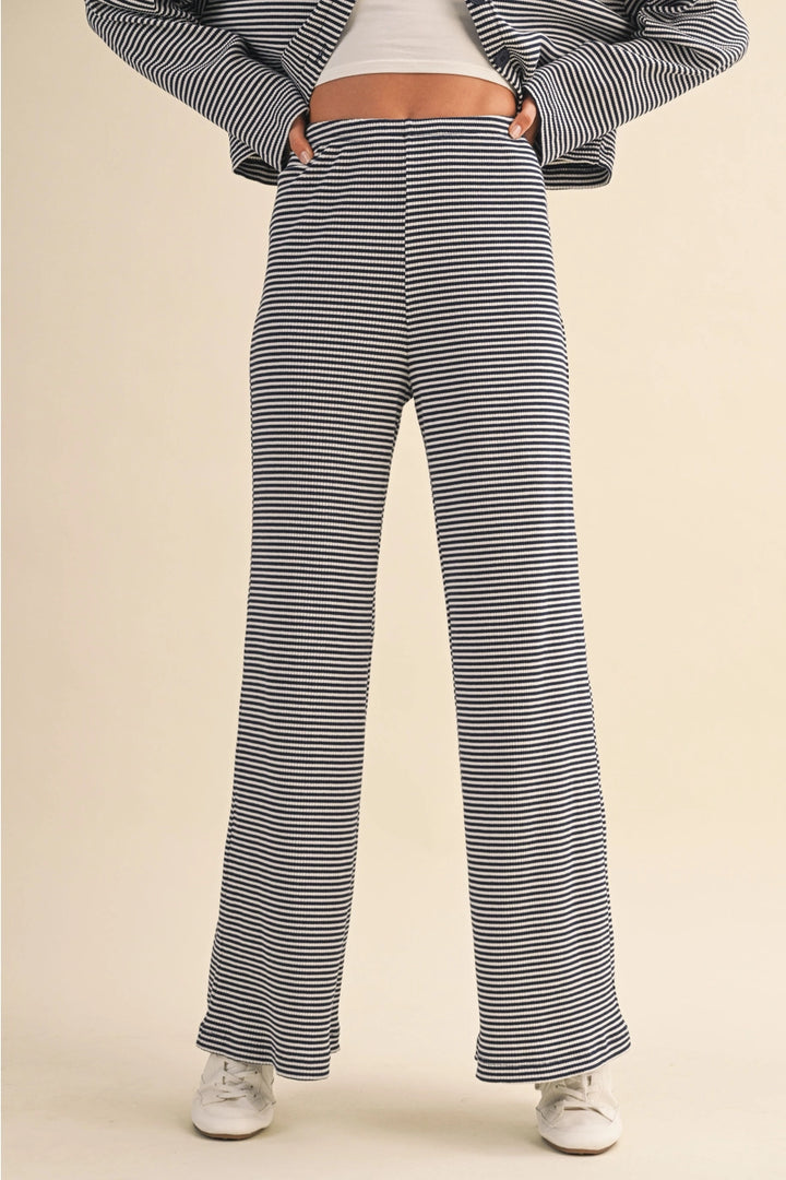 Person wearing navy and white striped pants on a beige background