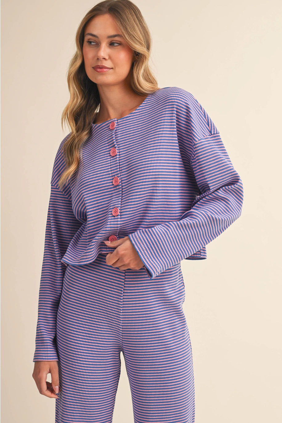 Woman wearing a purple and white striped pajama set on a beige background