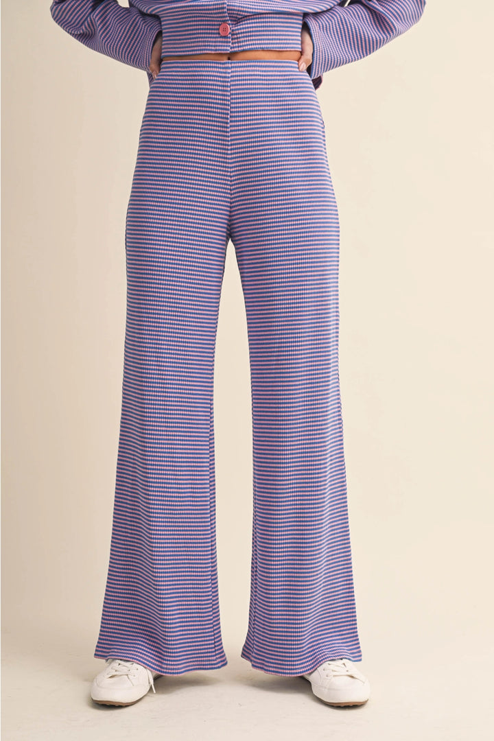 Person wearing a purple and white striped outfit with wide-leg pants on a beige background