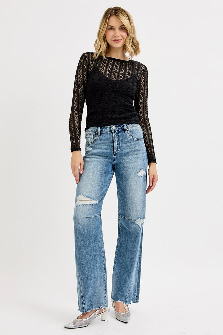 Woman wearing a black lace top and blue jeans on a white background
