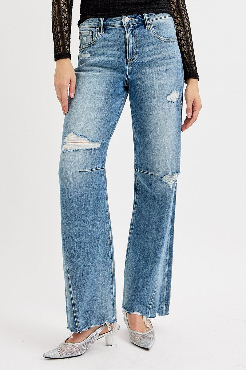 Person wearing distressed blue jeans on a white background