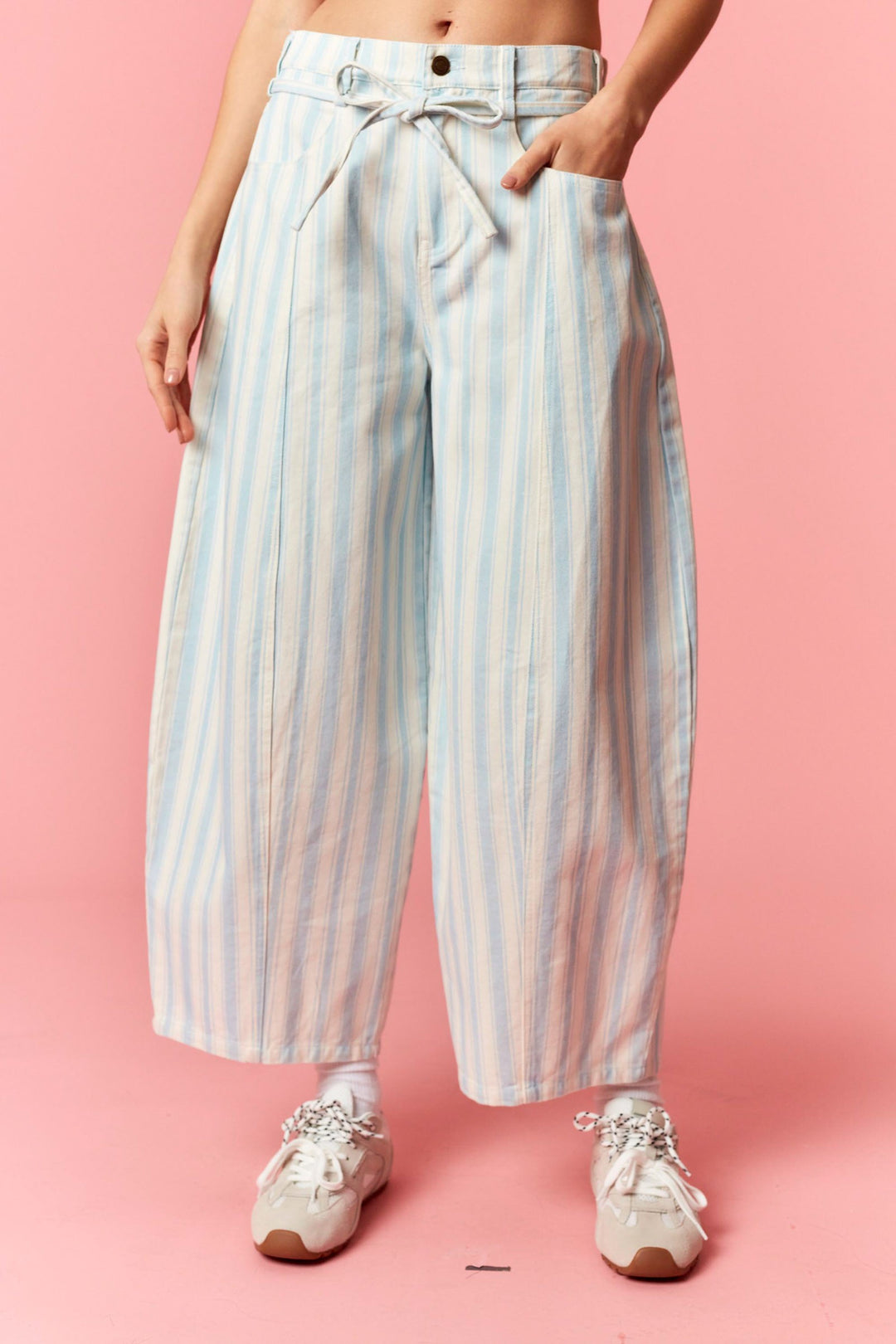 Person wearing blue and white stripe barrel pants on pink background