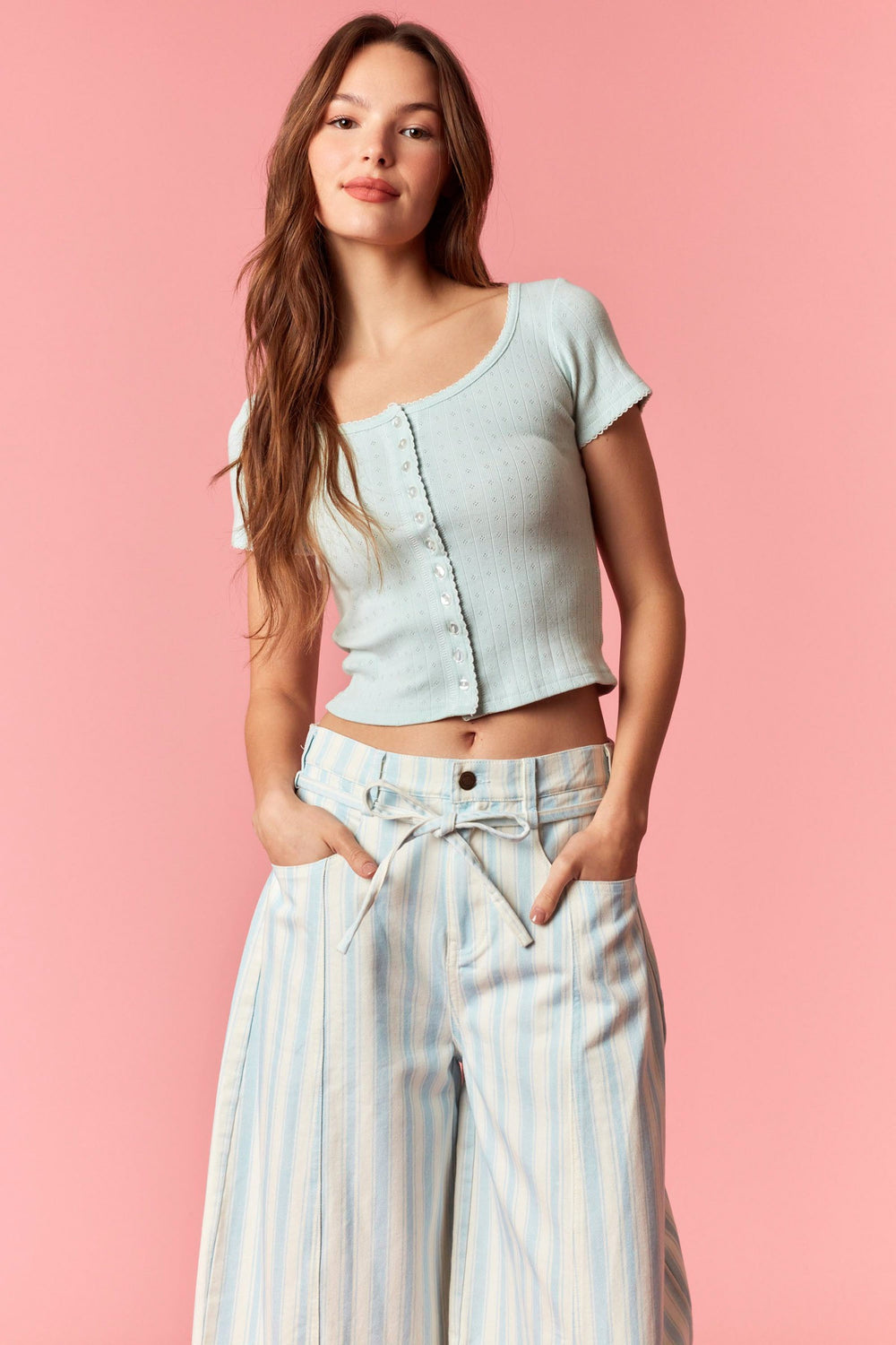Person wearing blue and white stripe pants with blue top on pink background