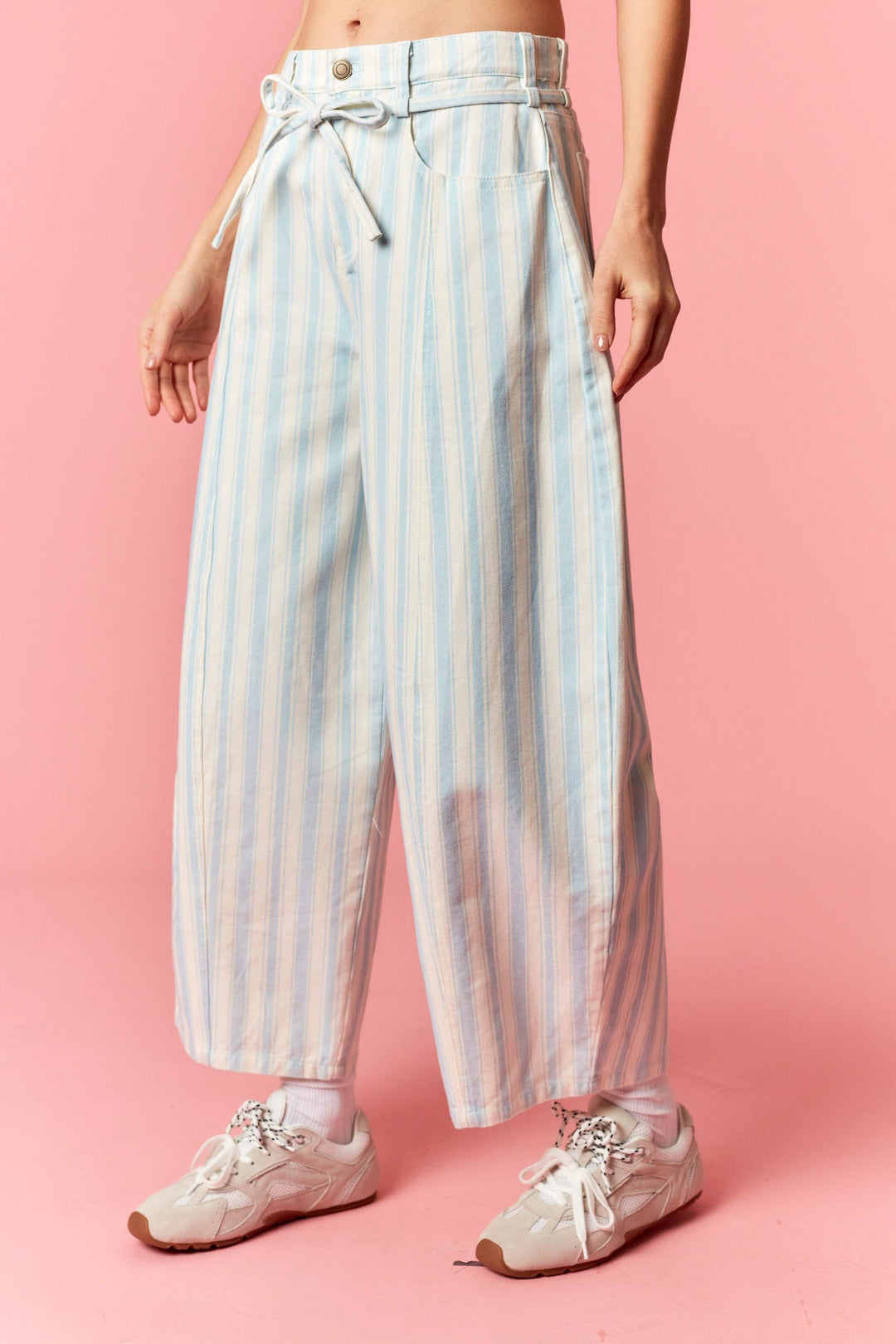 Person wearing blue and white stripe pants on pink background