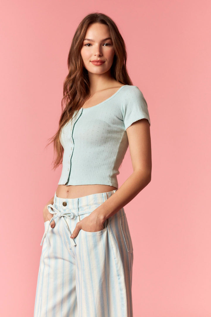 Person wearing blue and white stripe pants and blue top on pink background