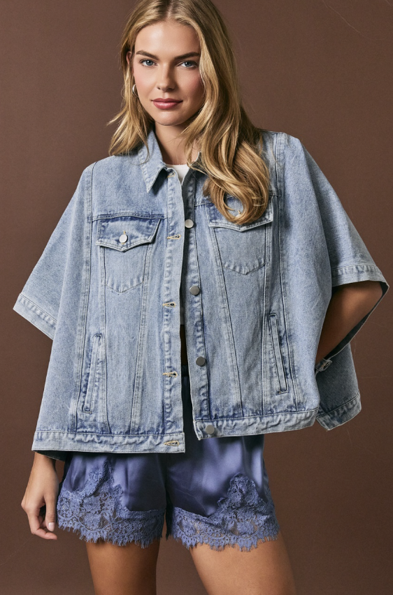 Woman wearing denim cape jacket and silk shorts on brown background