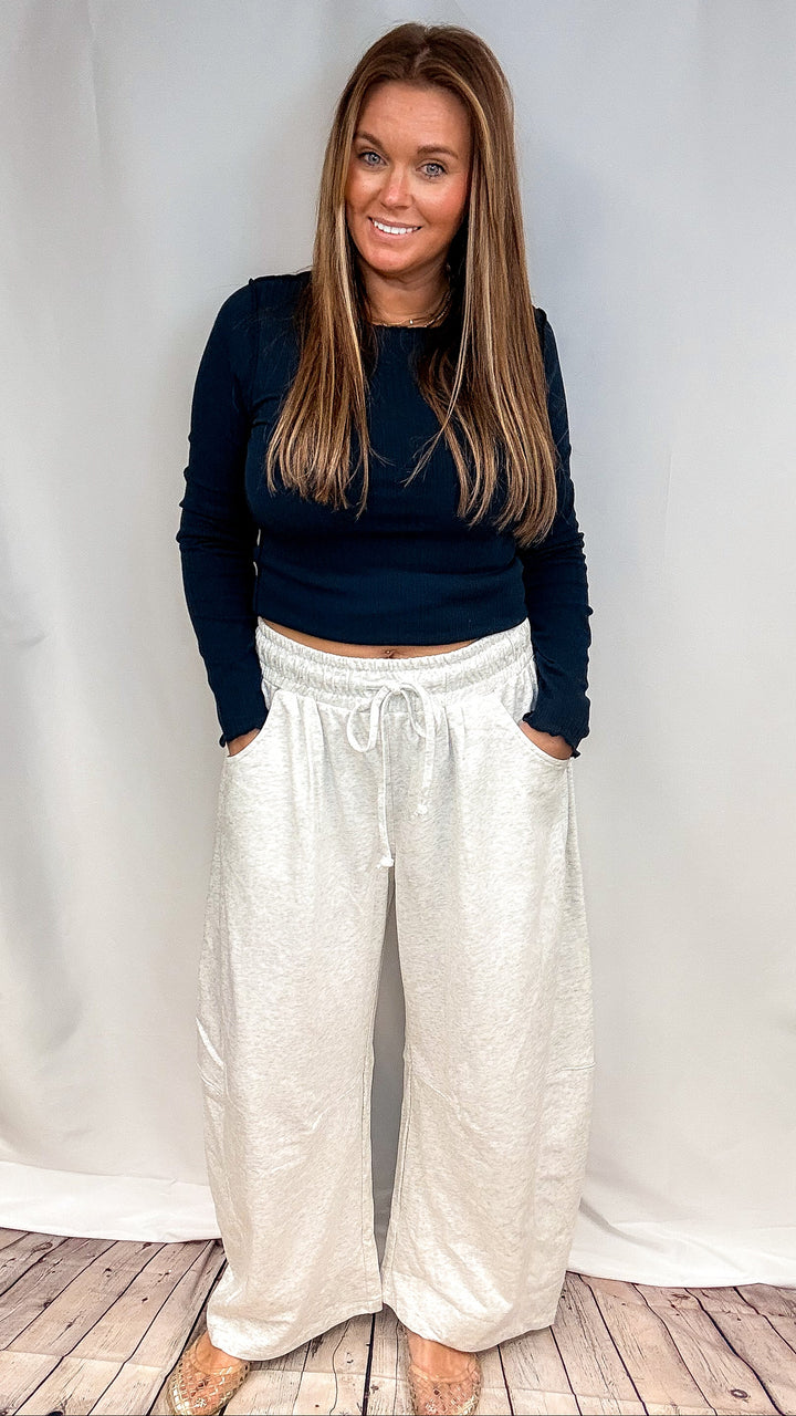 Woman wearing navy long sleeve shirt and grey sweatpants on plain background