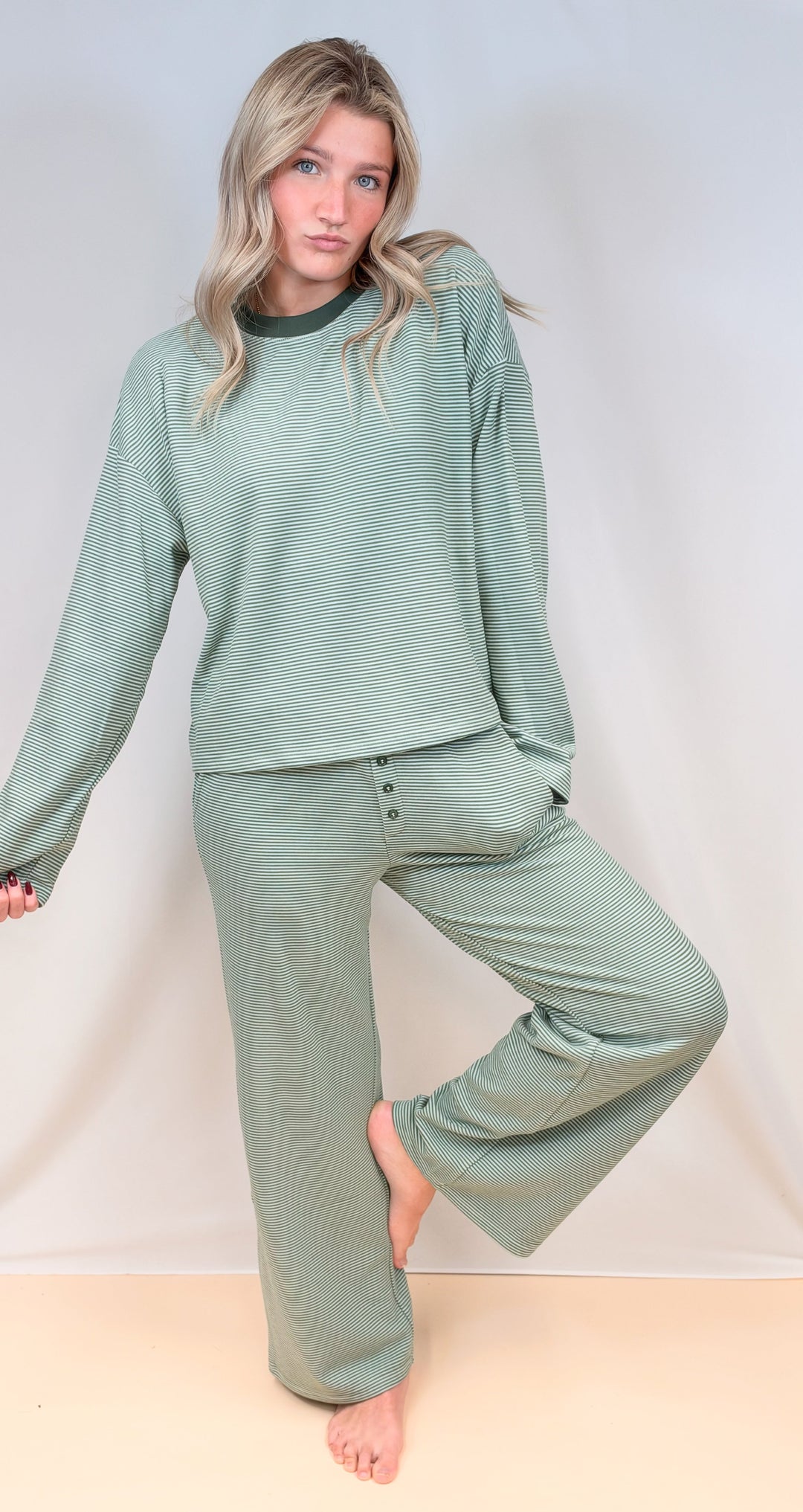 Woman wearing green and cream pinstripe matching set on plain background