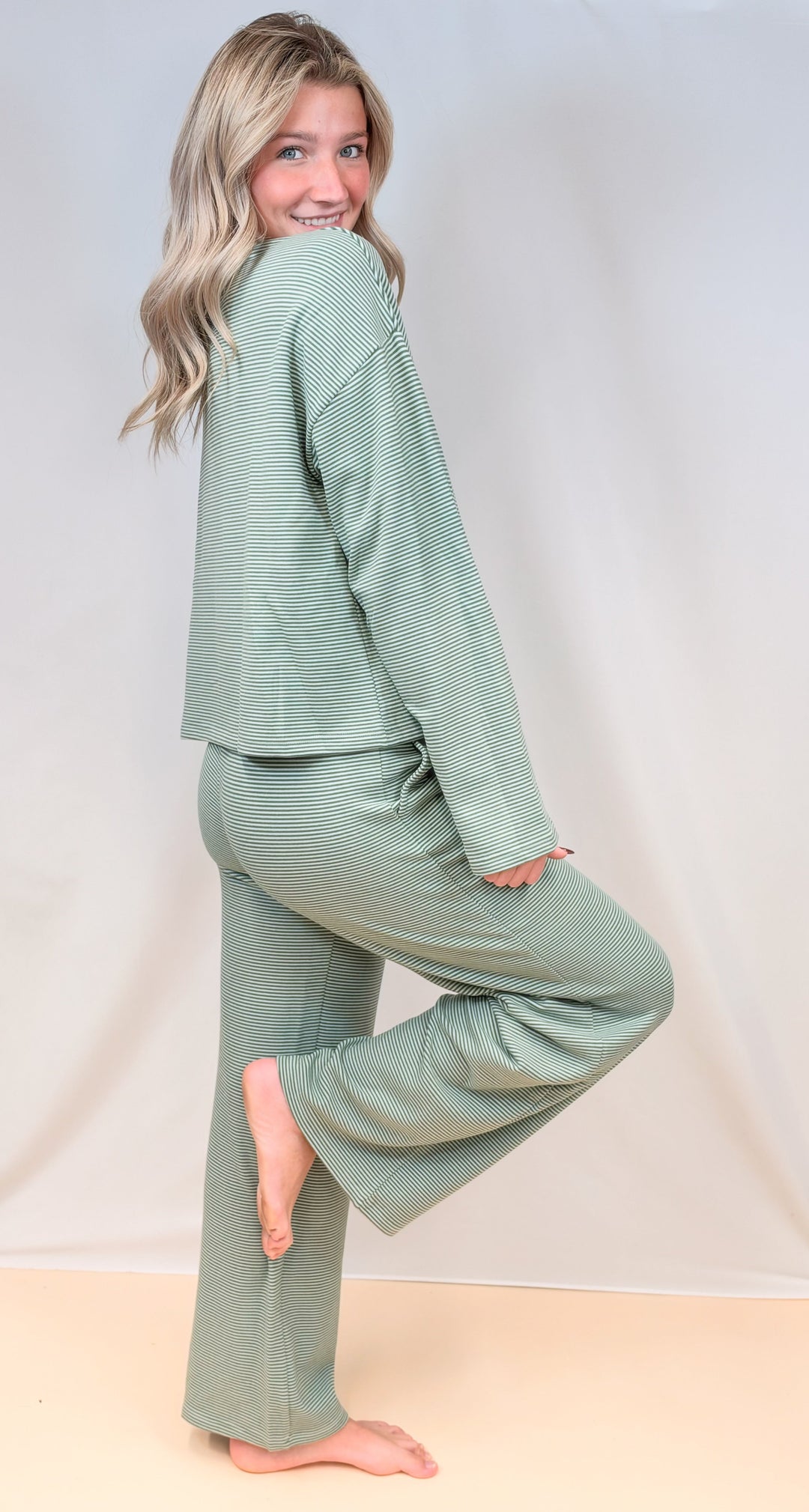 Woman shown from side view wearing green pin stripe set on plain background
