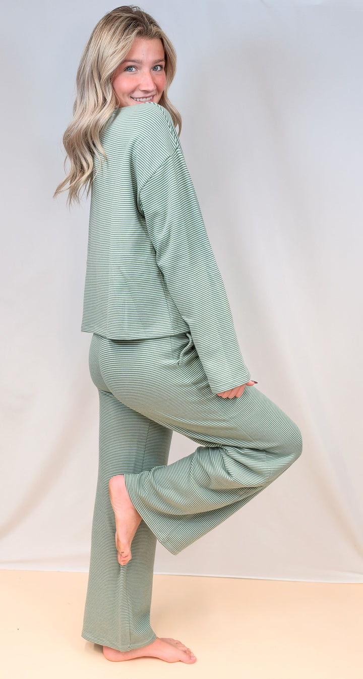 Woman shown from side view wearing green pin stripe set on plain background