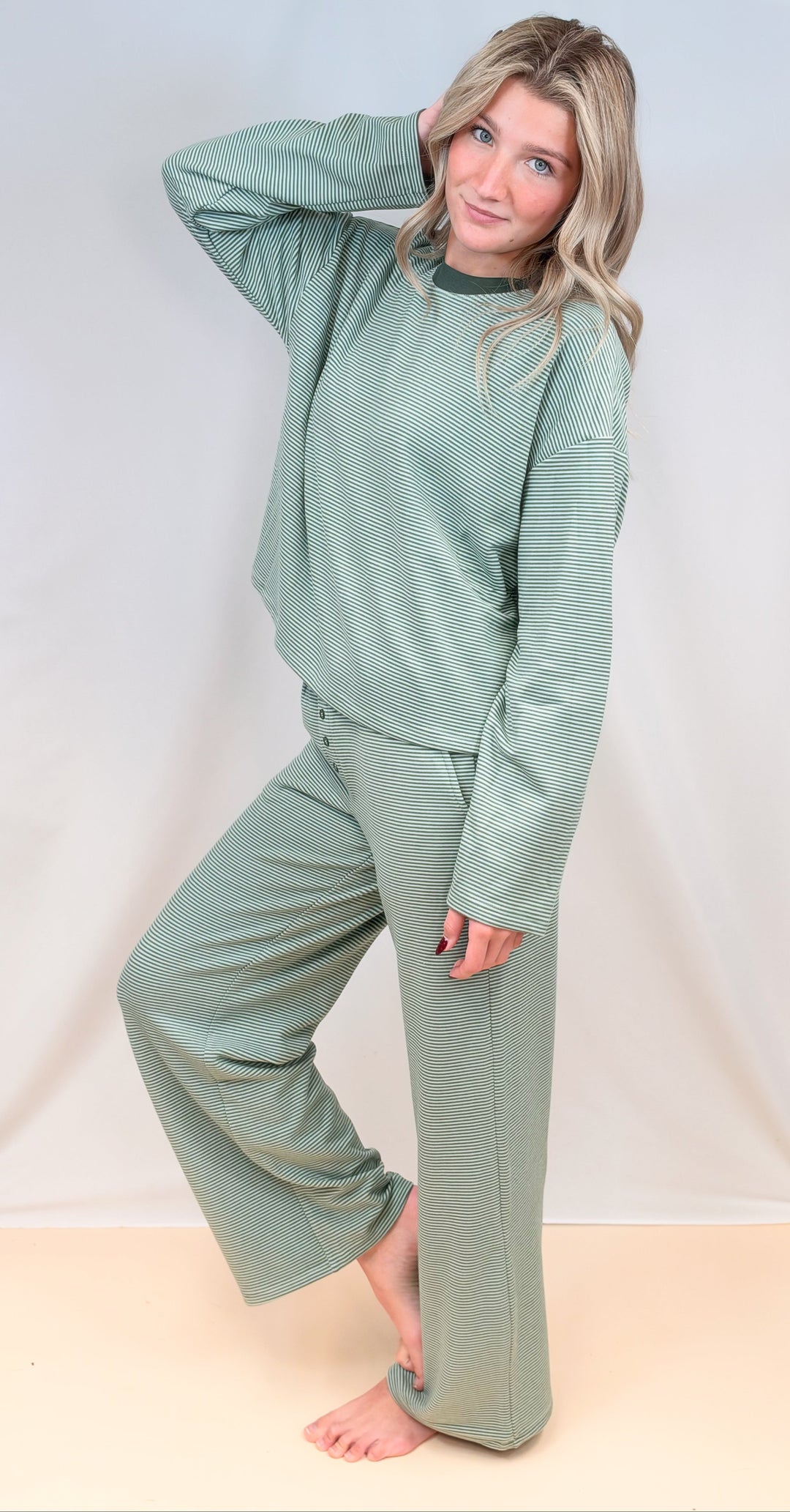 Woman wearing green and cream pin stripe matching set on plain background