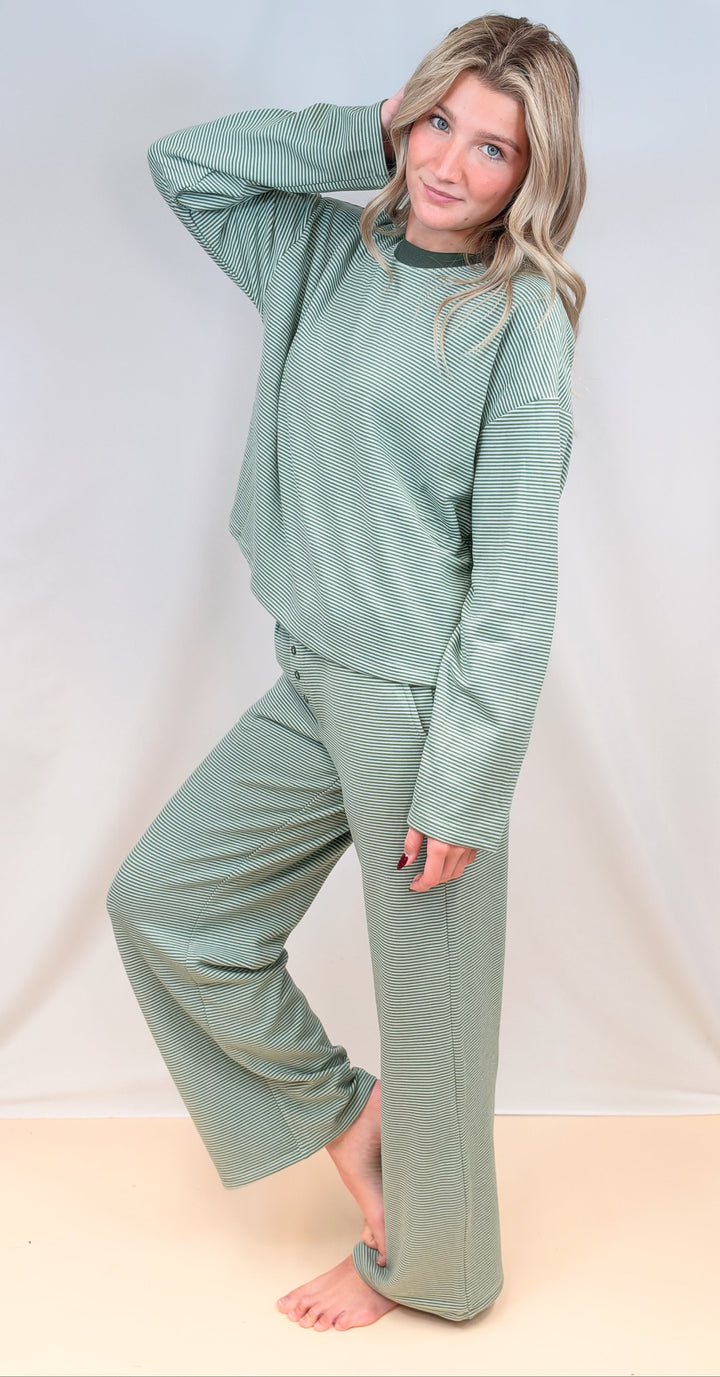 Woman wearing green and cream pin stripe matching set on plain background