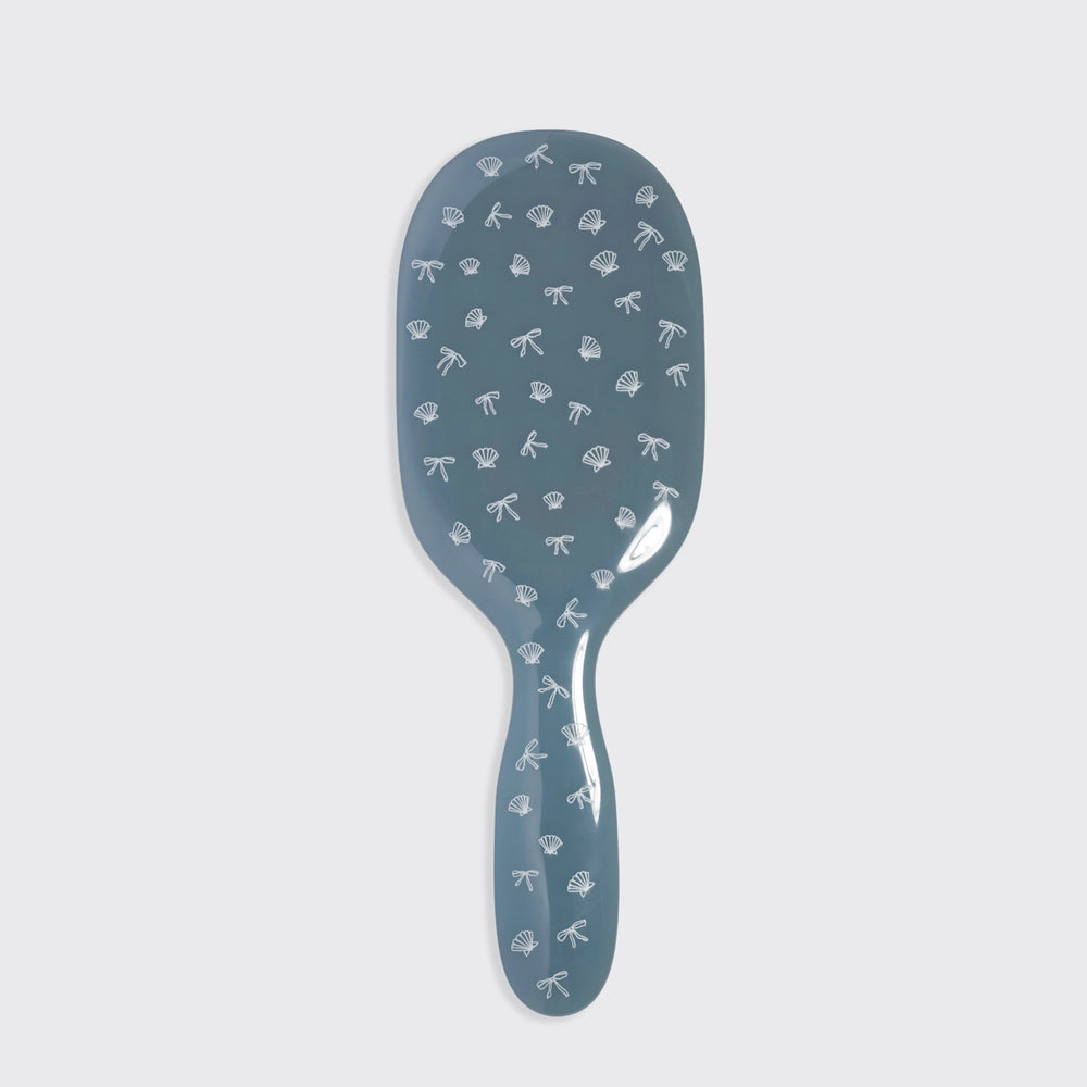 Blue hairbrush with decorative patterns on a light gray background