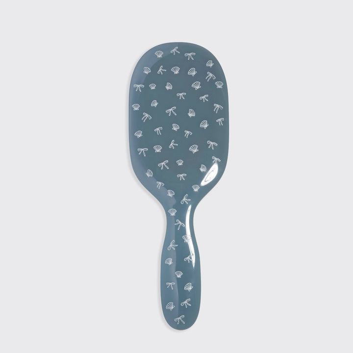 Blue hairbrush with decorative patterns on a light gray background