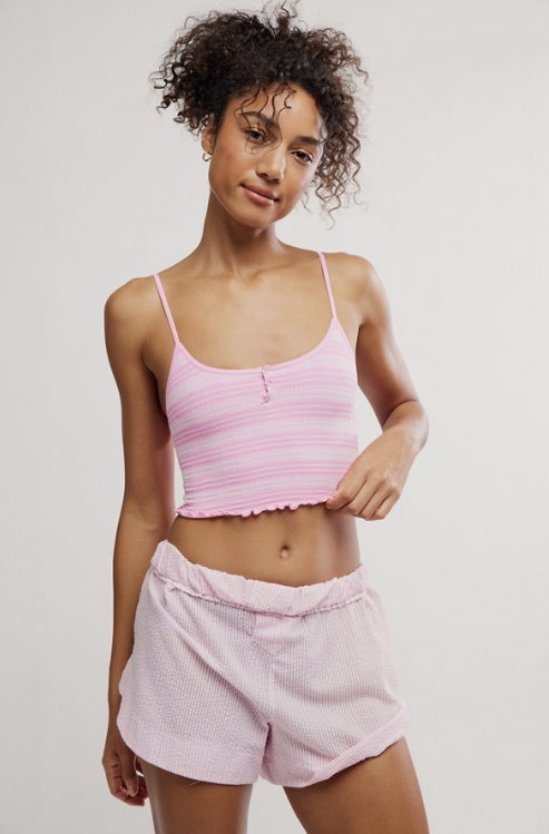 Woman wearing striped pink henley crop and shorts on plain background