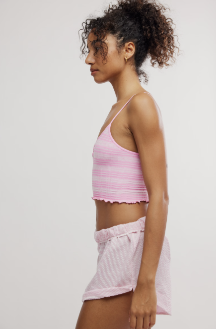 Woman wearing pink stripe henley crop with shorts on plain background
