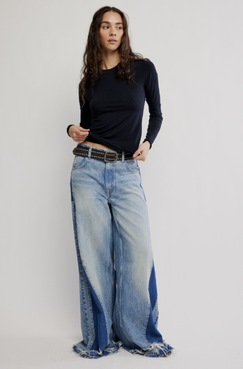 Woman wearing black long sleeve ribbed top and jeans on white background