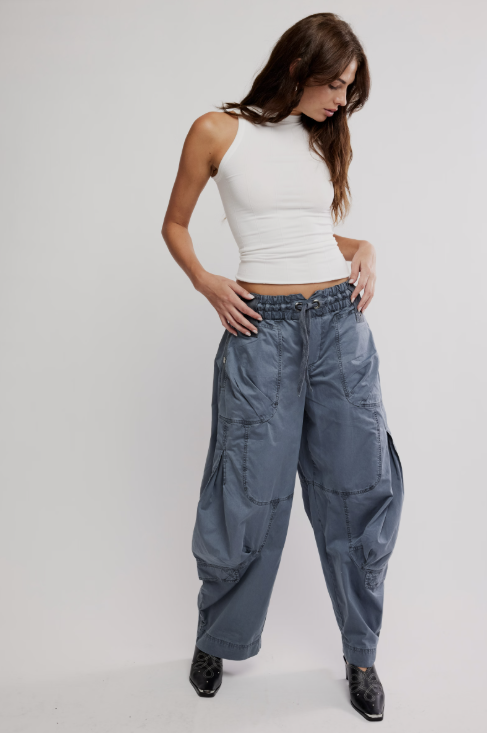 Woman wearing a white top and blue cargo pants on a plain background