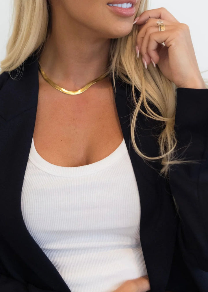 Woman wearing black jacket and white tee with gold chain necklace