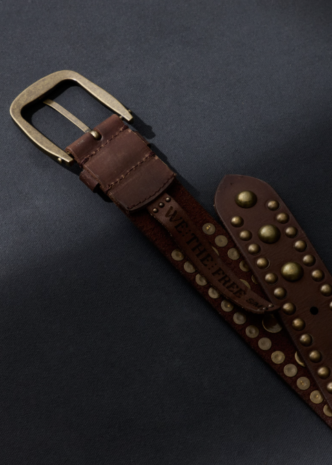 Brown studded belt with gold accents on plain dark background