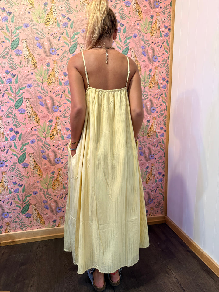 Woman wearing yellow pinstripe dress on floral background